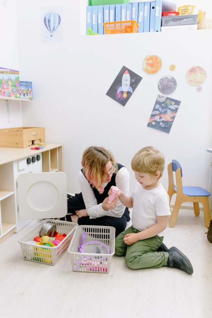A teacher and child playing with toys in a classroom setting, fostering interactive learning.
